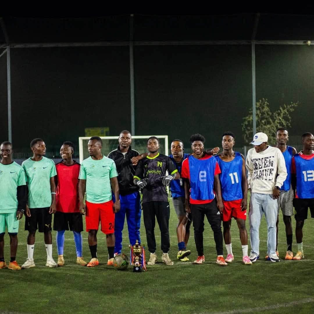 Madfutsal champions posing with the trophy under floodlights
